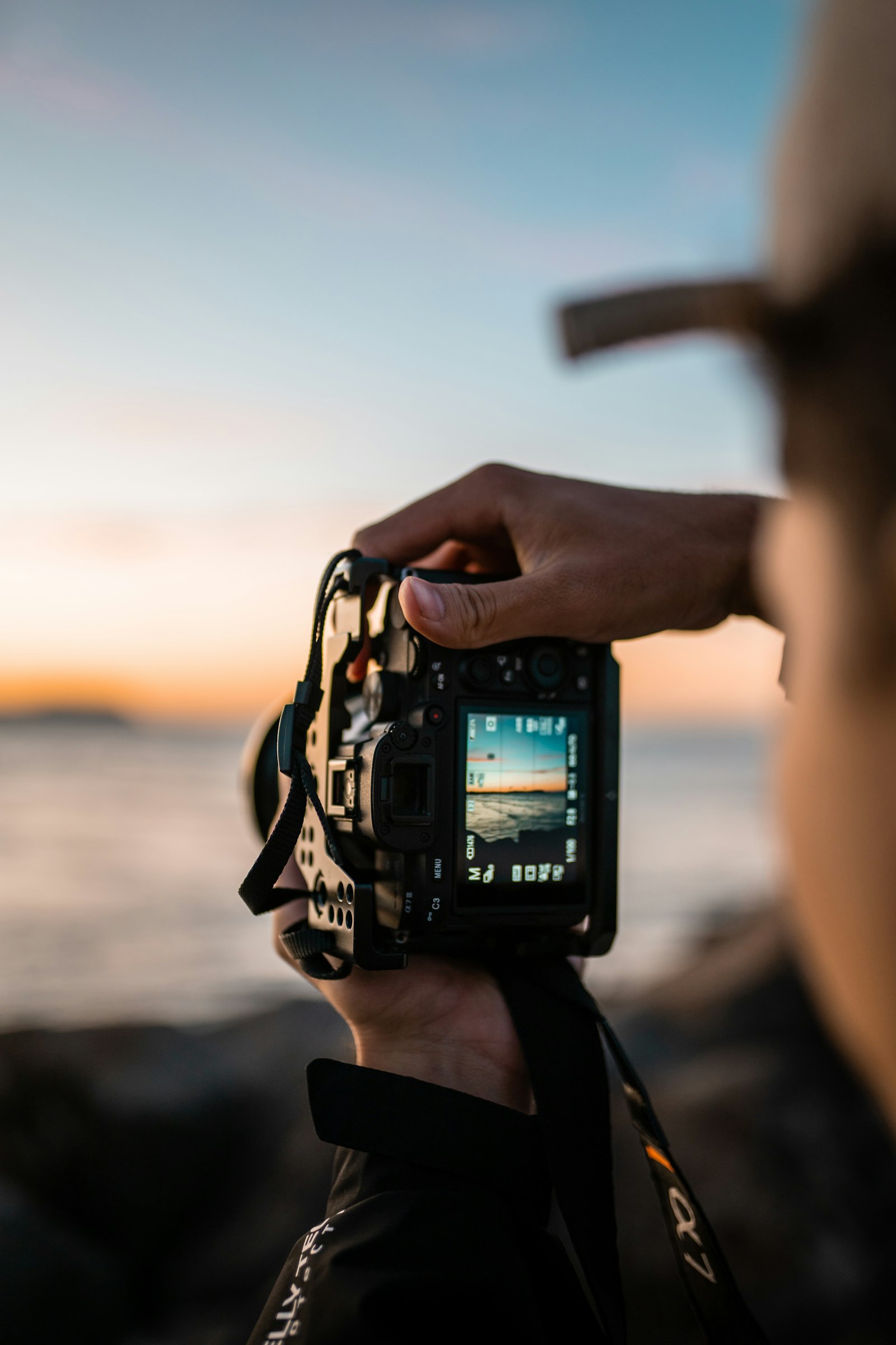 Fotograf hält eine DSLR-Kamera im Gegenlicht am Meer